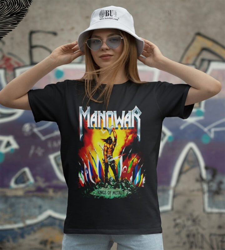 Renkli "Manowar" metal grubunun temalı tişört giyen kadın, sokak sanatı arka planı ile görsel şık ve enerjik görünüyor.