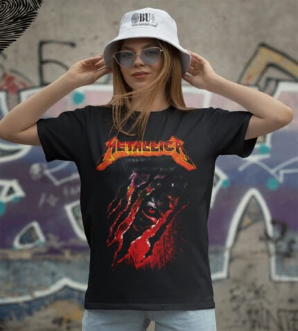 Metallica tişört, genç kadın giyiyor, graffiti arka planlı outdoor moda, rock müzik tutkusu, kısa kollu tişört, alternatif tarz, cool görünüm, gençlik ve müzik kültürü, genç stil, rahat günlük kıyafet, müzik severler için ideal.