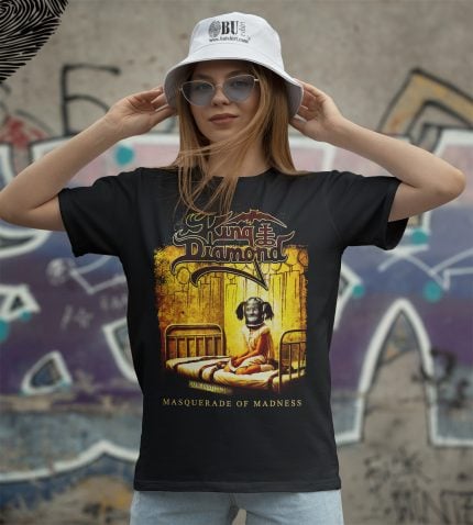 Kadın model üzerindeki siyah tişört, "King of Diamond" ve "Masquerade of Madness" yazılı grafikle tasarlanmış, maskeli çocuk figürü ve renkli detaylar içerir, genç ve modern giyim tarzı için idealdir.